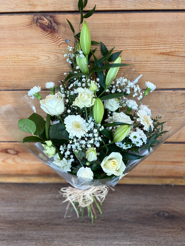 Bouquet of white flowers with green leaves on a wooden surface