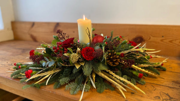 Traditional Christmas Table Decoration with a Candle. Festive foliage and flower arrangement. Same day delivery in Bournemouth.